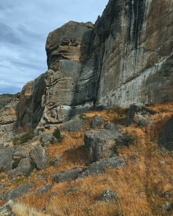 La pared de conglomerado del Cerro Benítez con escaladores diminutos en la base